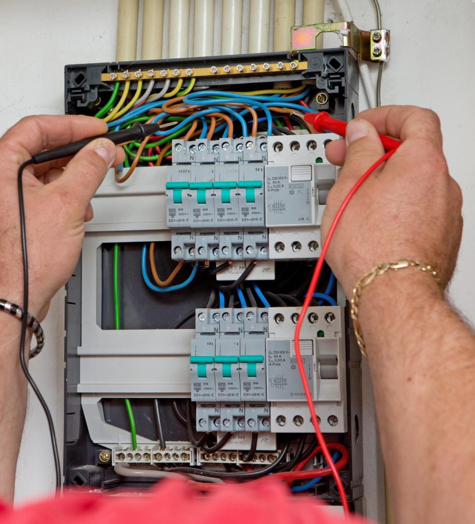 Electrician using a multimeter to perform electrical fault finding