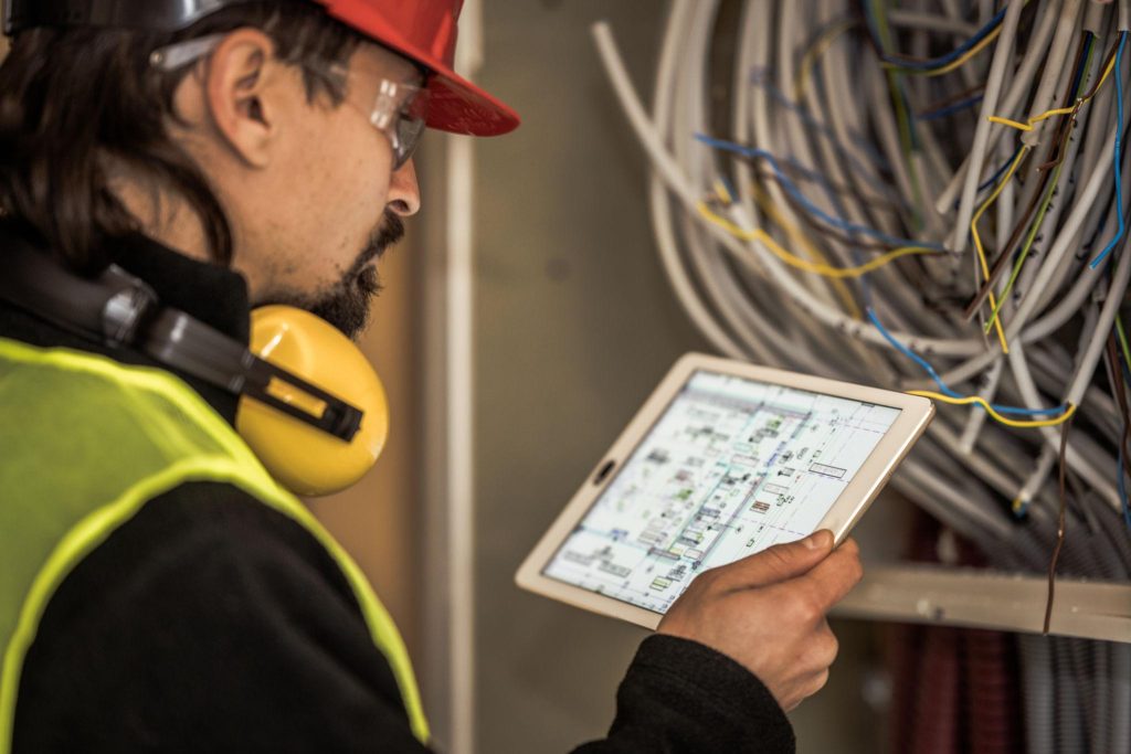 Electrician reviewing electrical plans and compliance documents during inspection